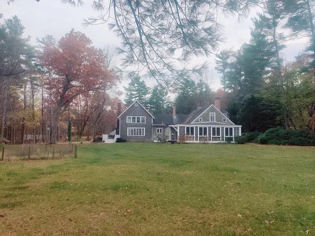 a view of a big house with a big yard and large trees