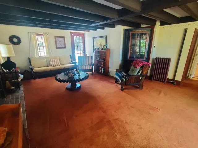 a living room with furniture a rug a fireplace and a large window