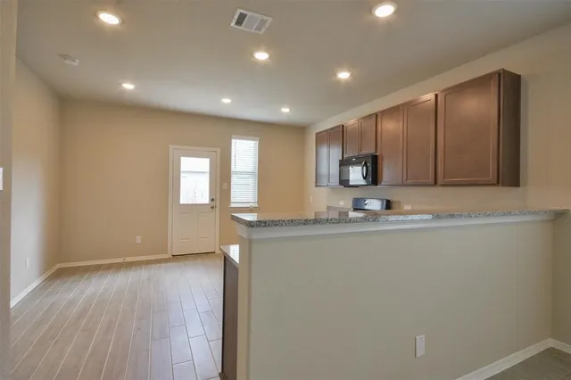 a kitchen with granite countertop cabinets stainless steel appliances a sink and a window