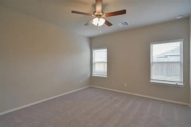 an empty room with windows and fan