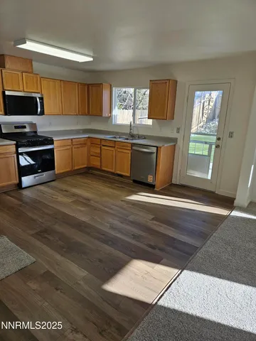 a kitchen with stainless steel appliances wooden cabinets a stove a sink and a microwave