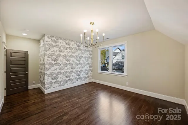 an empty room with wooden floor chandelier and windows