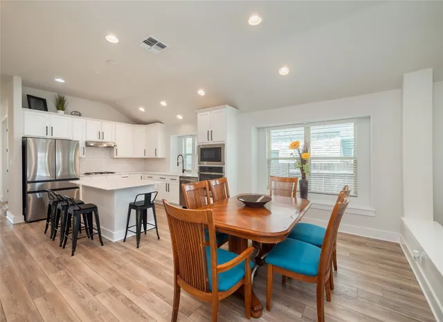 a dining room with stainless steel appliances kitchen island granite countertop a dining table chairs and white cabinets