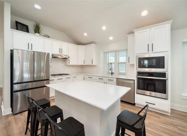 a kitchen with a refrigerator a stove a sink and chairs