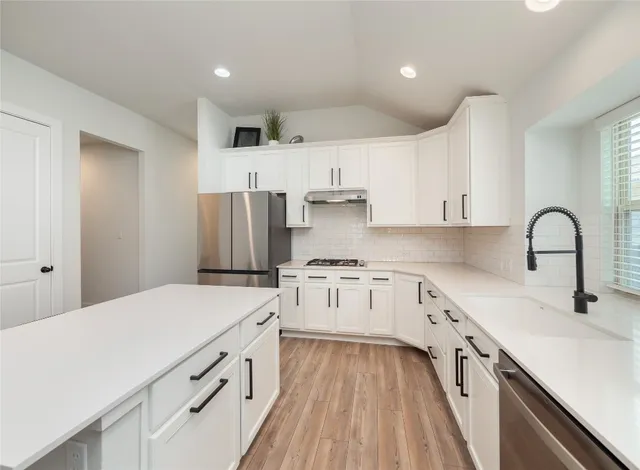 a kitchen with kitchen island white cabinets and stainless steel appliances