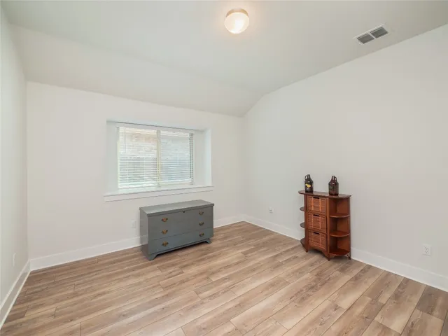 an empty room with wooden floor and cabinet