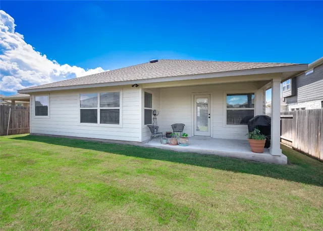 a view of a back yard with an tree and wooden fence