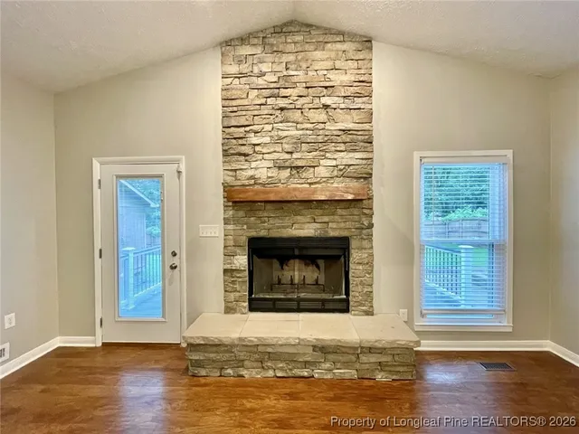 a view of an empty room with wooden floor and a fireplace