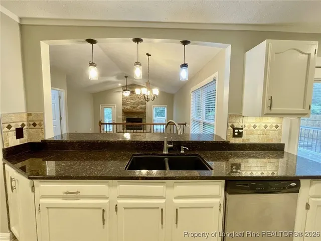 a kitchen with granite countertop a stove a sink and a microwave