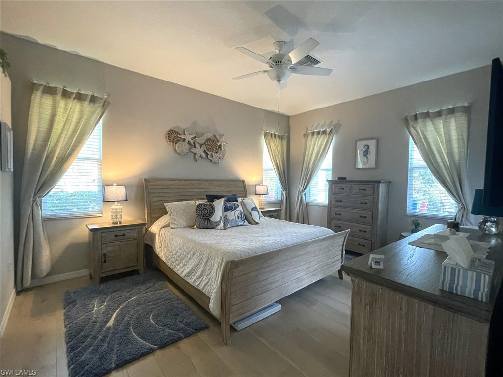 3532 Periwinkle Way, Unit 11 Naples, FL 34114 - Photo 15 of 37 a spacious bedroom with a large bed and a chandelier