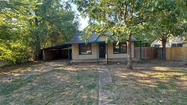 a view of a house with a yard and large tree