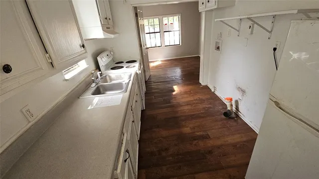 an empty room with wooden floor cabinet and windows