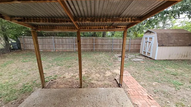 a backyard of a house with a large tree and wooden fence