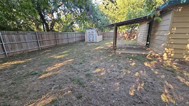 a view of a backyard with large trees and wooden fence