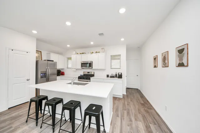 a kitchen with stainless steel appliances a table and chairs in it