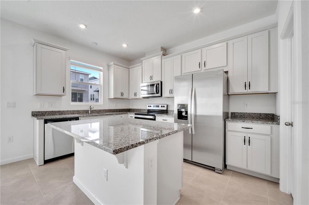 9068 Ocean Tide Way Kissimmee, FL 34747 - Photo 12 of 42 a kitchen with stainless steel appliances granite countertop a sink stove and refrigerator