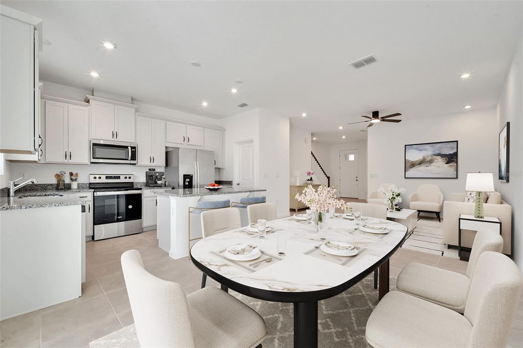 9068 Ocean Tide Way Kissimmee, FL 34747 - Photo 13 of 42 a open kitchen with stainless steel appliances kitchen island granite countertop a sink a stove a dining table and chairs