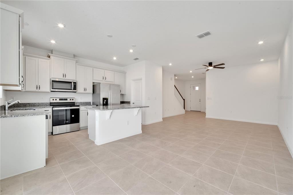9068 Ocean Tide Way Kissimmee, FL 34747 - Photo 14 of 42 a large kitchen with kitchen island a stove a sink a refrigerator and white cabinets