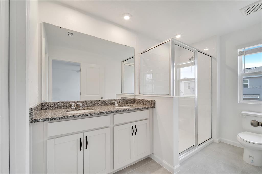 9068 Ocean Tide Way Kissimmee, FL 34747 - Photo 23 of 42 a bathroom with a granite countertop sink a toilet and a mirror
