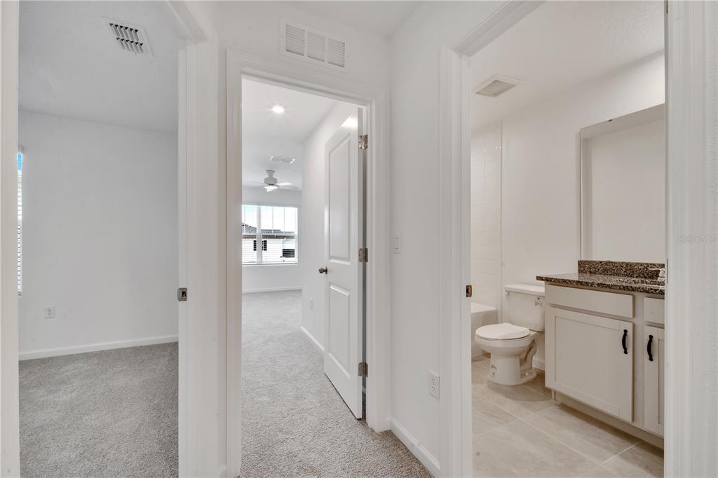 9068 Ocean Tide Way Kissimmee, FL 34747 - Photo 28 of 42 a bathroom with a granite countertop toilet a sink and a mirror