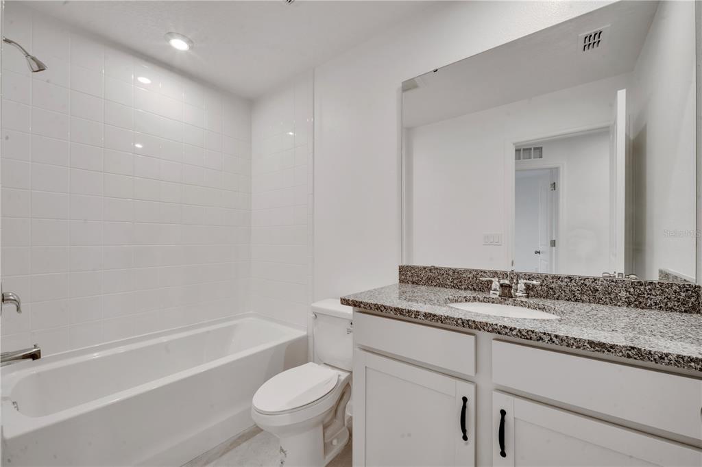 9068 Ocean Tide Way Kissimmee, FL 34747 - Photo 29 of 42 a bathroom with a granite countertop sink a toilet and bathtub