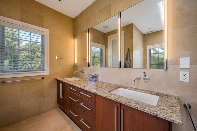 a bathroom with a granite countertop sink and a large mirror