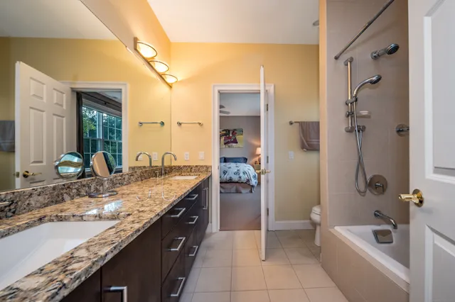 a bathroom with a granite countertop bathtub a sink and a mirror