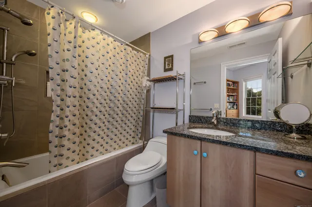a bathroom with a granite countertop toilet a sink and a mirror