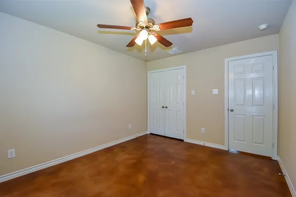 an empty room with a chandelier fan and closet