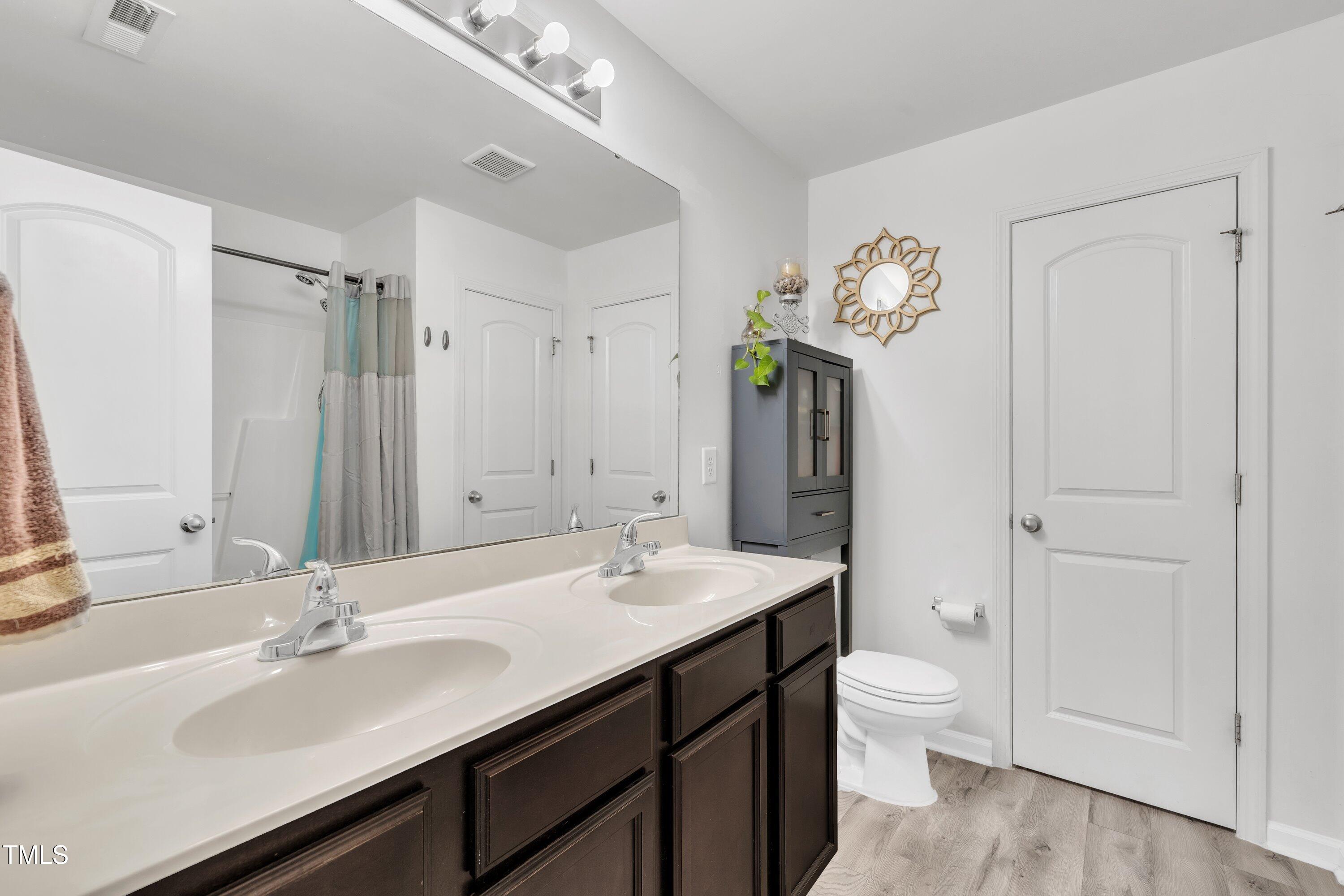 2816 Erinridge Road Raleigh, NC 27610 - Photo 8 of 20 a bathroom with a sink a toilet and a large mirror
