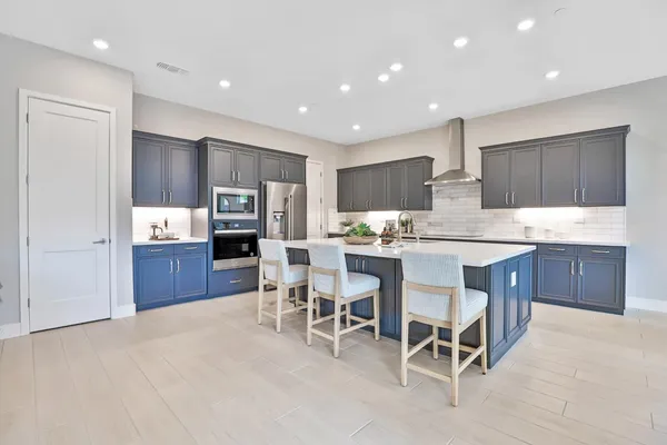a kitchen with stainless steel appliances kitchen island granite countertop a refrigerator and microwave