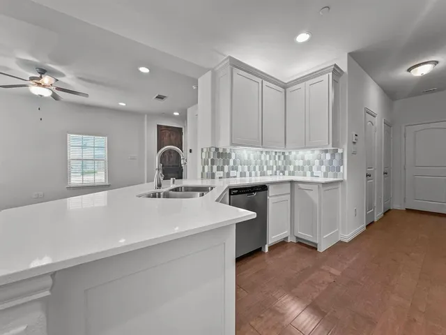 a view of cabinets a sink wooden floor and windows in a room