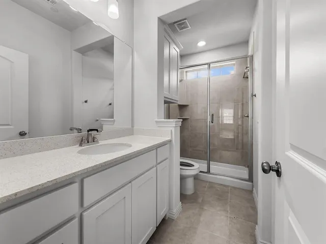 a bathroom with a double vanity sink toilet mirror and shower