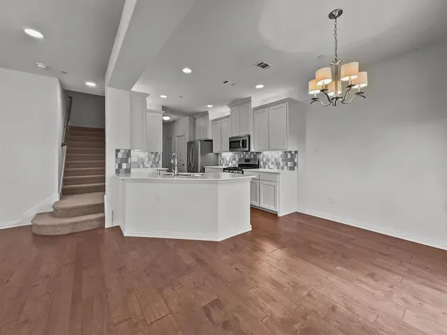 a view of a kitchen with kitchen island stainless steel appliances a sink a refrigerator and a counter top space