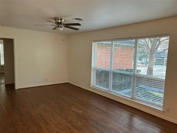 a view of an empty room with a window and wooden floor