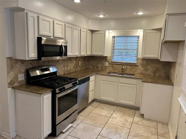 a kitchen with granite countertop a sink a stove and cabinets