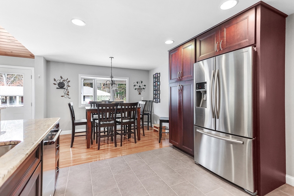 86 Butternut Lane Methuen, MA 01844 - Photo 12 of 32 a kitchen with stainless steel appliances granite countertop a refrigerator a stove a dining table and chairs with wooden floor