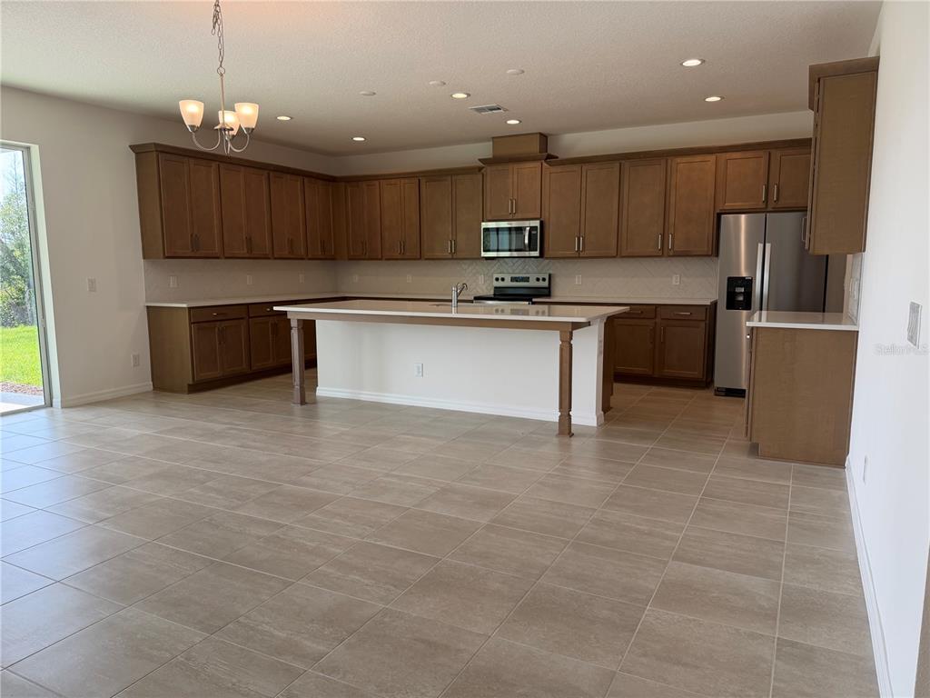 756 Farfields Street DeLand, FL 32724 - Photo 3 of 13 a kitchen with kitchen island a counter top space appliances and a cabinets