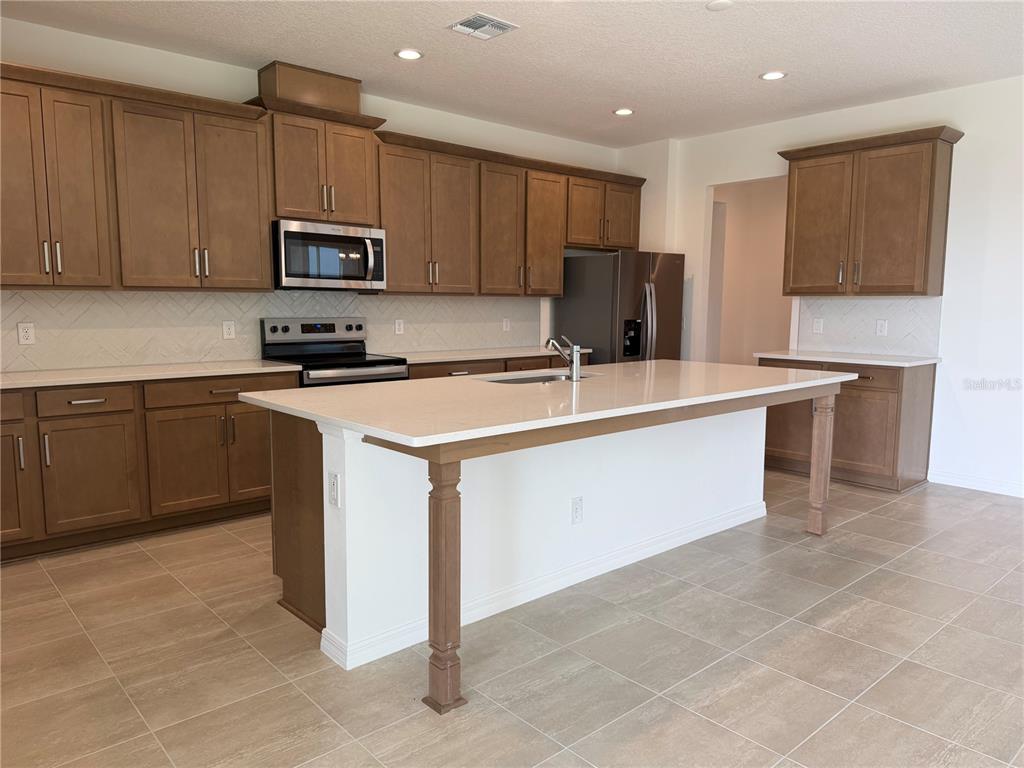 756 Farfields Street DeLand, FL 32724 - Photo 5 of 13 a kitchen with stainless steel appliances granite countertop a stove top oven a sink a refrigerator and white cabinets