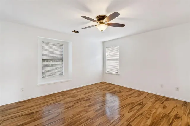 a view of empty room with wooden floor and ceiling fan