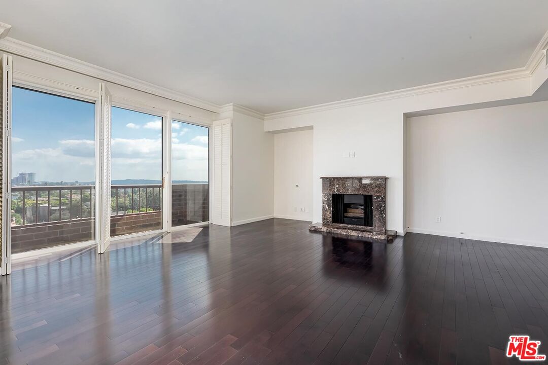 10550 Wilshire Boulevard, Unit 804 Los Angeles, CA 90024 - Photo 16 of 22 an empty room with floor to ceiling window wooden floor and a fireplace