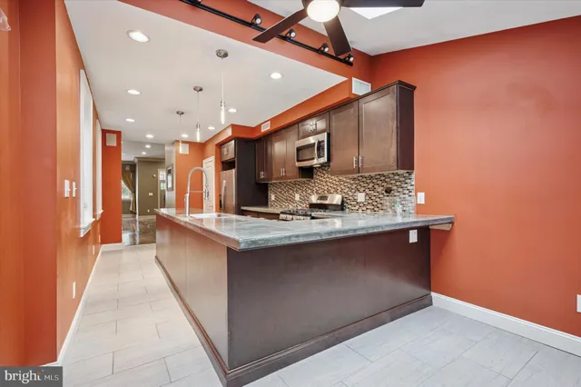 a view of kitchen island with stainless steel appliances granite countertop sink stove and refrigerator