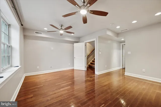 a view of an empty room with window and wooden floor
