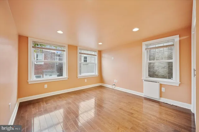 a view of an empty room with a window and wooden floor