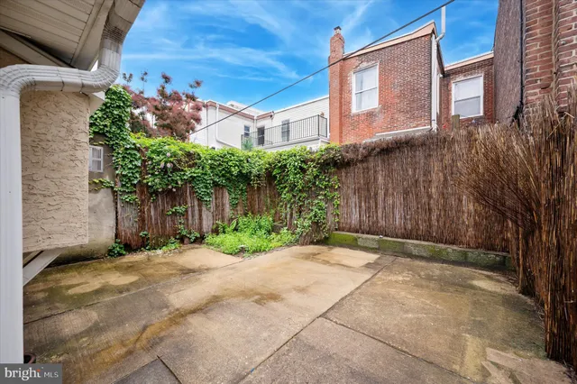 a backyard of a house with plants and trees with wooden fence