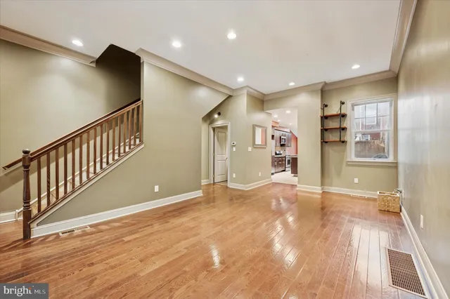 a view of an empty room with wooden floor and a bathroom
