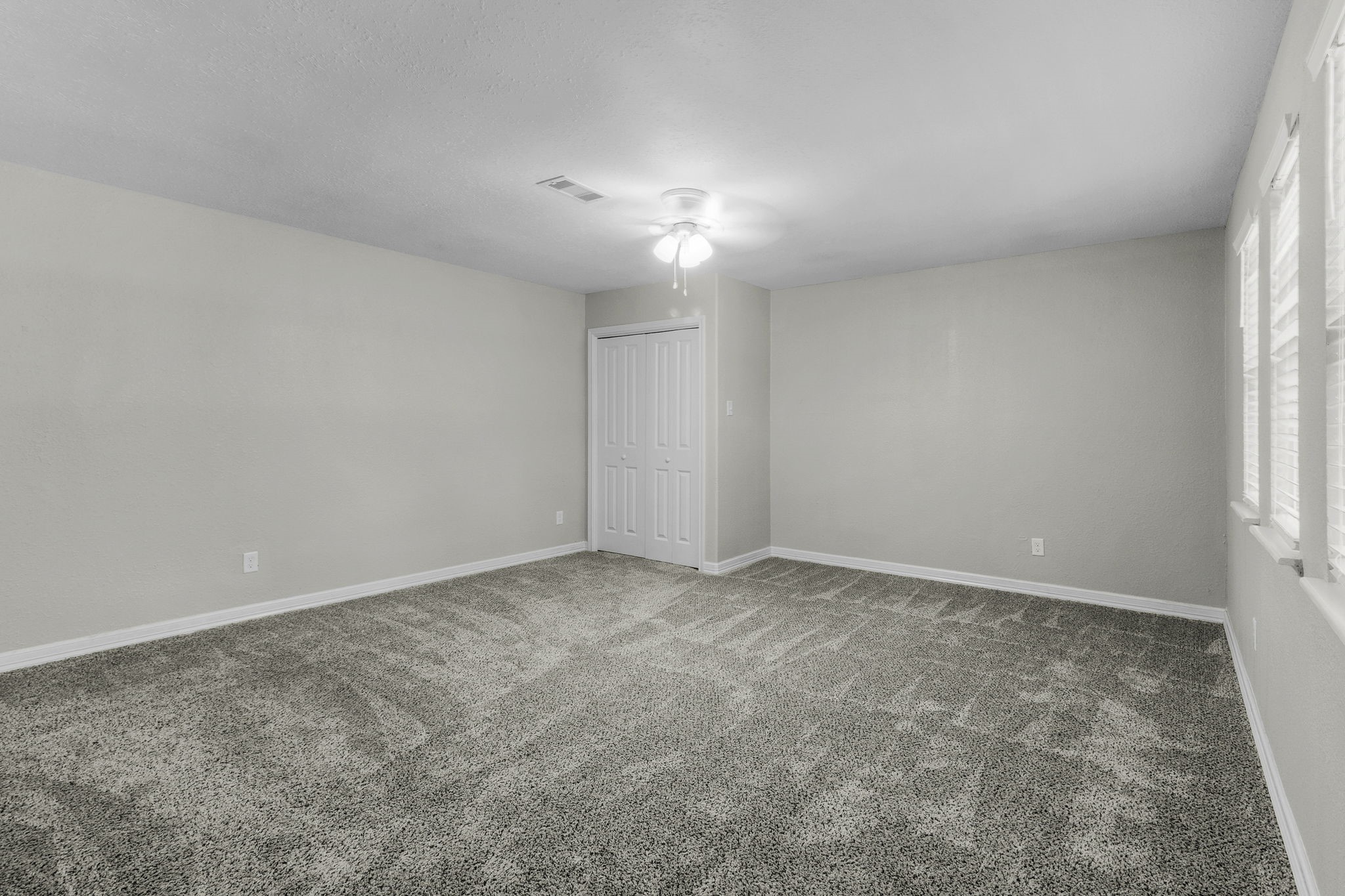 21 Red Oak Circle Point Blank, TX 77364 - Photo 10 of 32 This spacious, neutral-toned bedroom features plush carpeting, ample natural light from multiple windows, a ceiling fan, and a closet with double doors, perfect for comfort and storage.