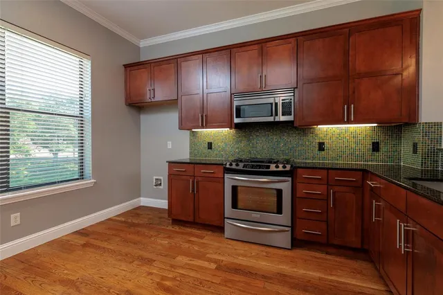 a kitchen with granite countertop wooden cabinets a stove a oven and a window