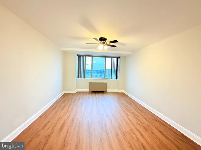 a view of an empty room with wooden floor and a window