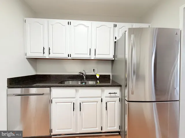 a kitchen with granite countertop a refrigerator sink and cabinets